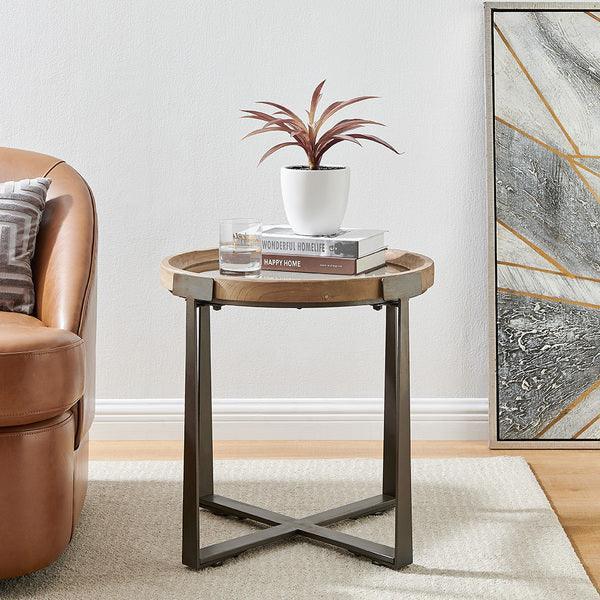 Round wooden side table with metal legs, houseplant, glass, books in modern living room