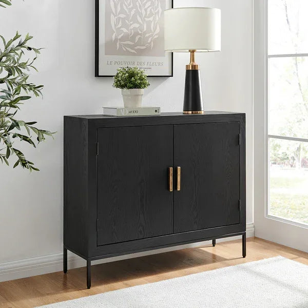 Black sideboard cabinet with gold handles, decorated with lamp and plant, in bright living room