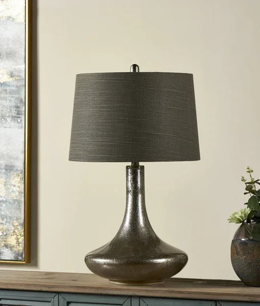 Smoky glass table lamp with dark grey fabric shade on wooden sideboard beside decor