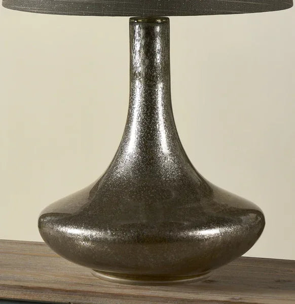 Glass table lamp with wide metallic base and black lampshade on wooden surface