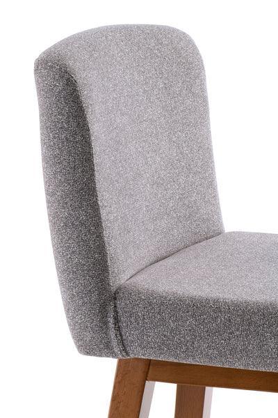 Grey fabric dining chair with padded backrest and wooden legs, side profile view