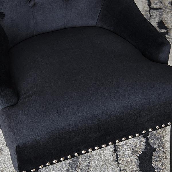 Black velvet armchair seat with silver stud detail and curved arm on patterned rug