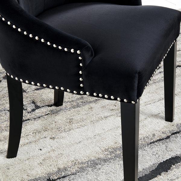 Black velvet dining chair with silver stud detailing and wooden legs on patterned rug