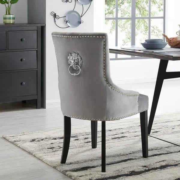 Grey velvet dining chair with silver lion knocker and studded trim in modern dining room