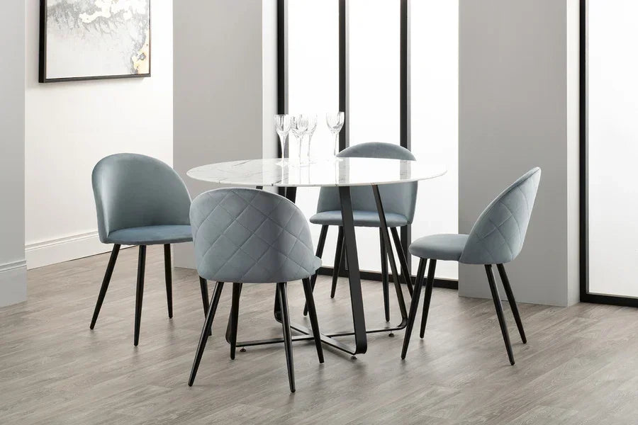 Round white marble dining table with four grey upholstered dining chairs, modern setting