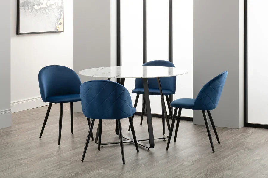 Round marble dining table with blue velvet chairs and black legs in modern room