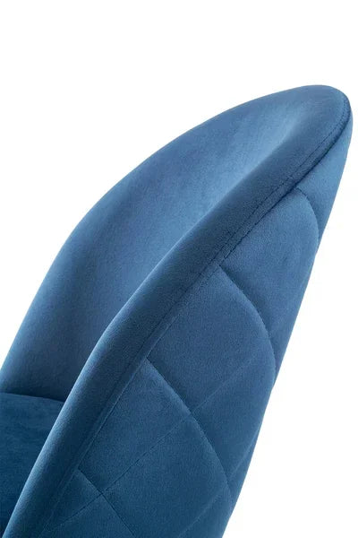 Closeup of blue velvet dining chair with quilted backrest upholstery