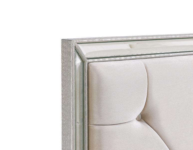 Close-up of mirrored bed headboard with light silver upholstered panel and textured frame