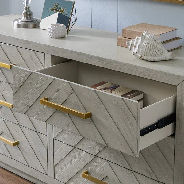 Wooden sideboard with chevron pattern, gold handles, open drawer, and decorative items