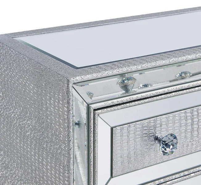 Silver mirrored chest of drawers with crystal handles and textured panel detail, corner view