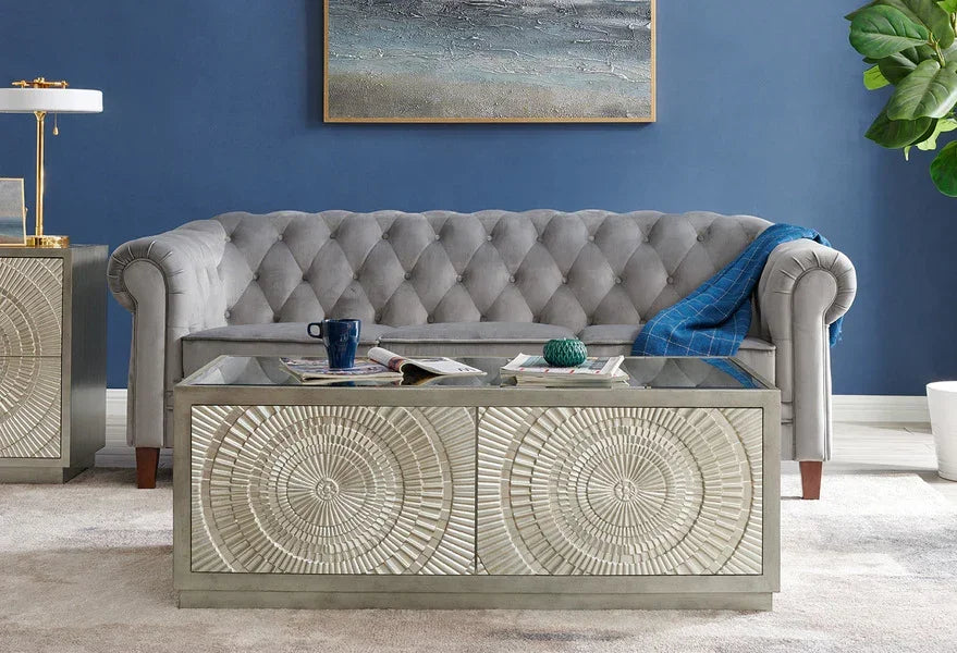 Grey velvet tufted sofa with patterned glass coffee table in modern living room
