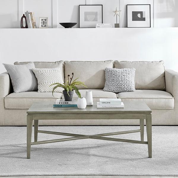 Beige fabric sofa with grey cushions behind a wooden coffee table in modern living room