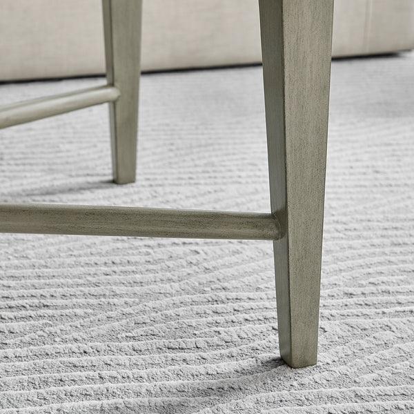 Grey wooden dining table leg on textured light grey carpet