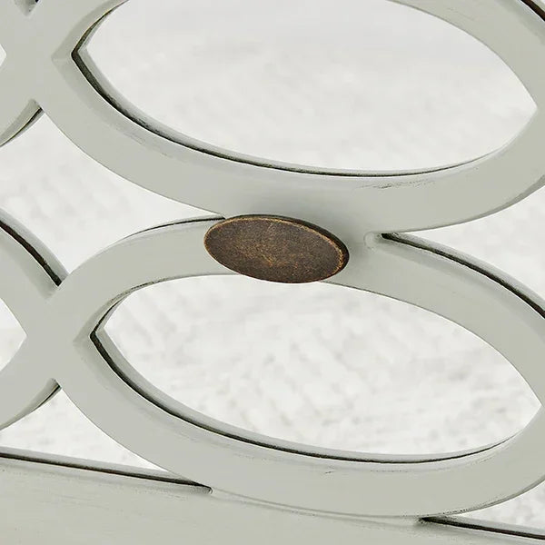 Closeup of metal furniture frame with decorative oval detail and bronze accent