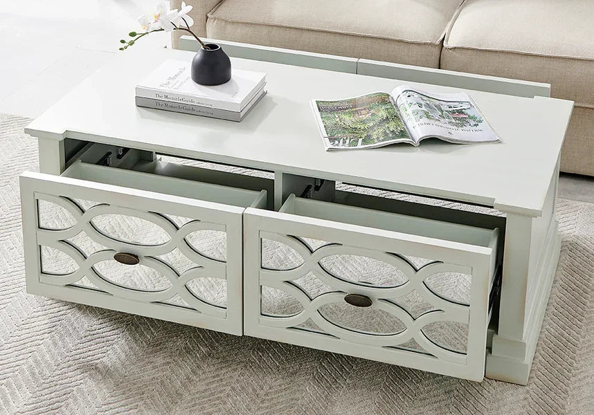 White coffee table with decorative drawers and storage, styled with books and a vase