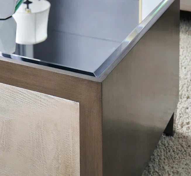 Glass top coffee table with wood panel detail on textured rug