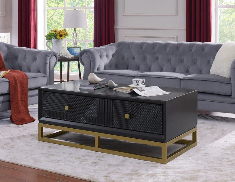Black wood coffee table with gold metal base in living room with grey tufted sofas