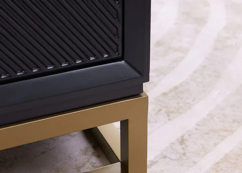Black sideboard with textured panel and gold metal frame base on patterned rug