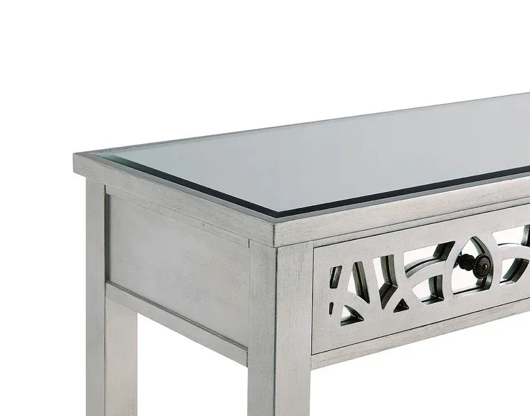 Silver console table with glass top and decorative carved drawer front
