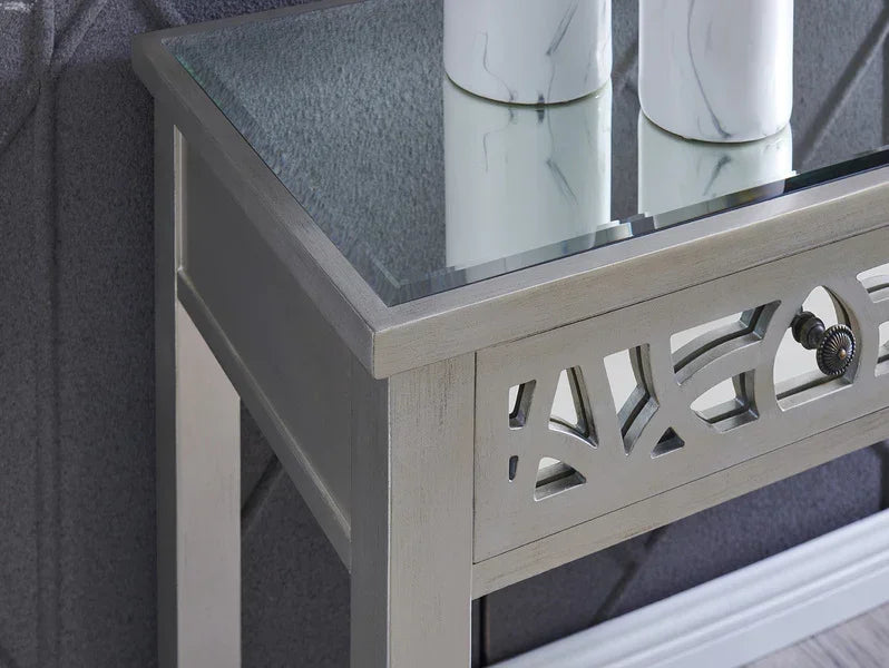 Silver mirrored console table with glass top and decorative drawer detail