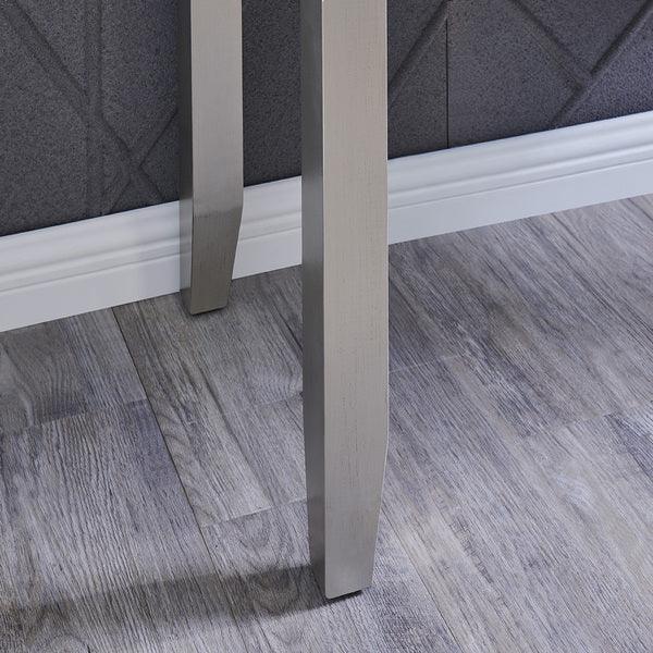 Brushed metal dining table legs on grey wood floor with textured wall background