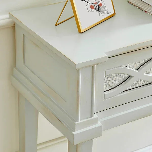 White wooden console table with carved front detail and decorative frame on top