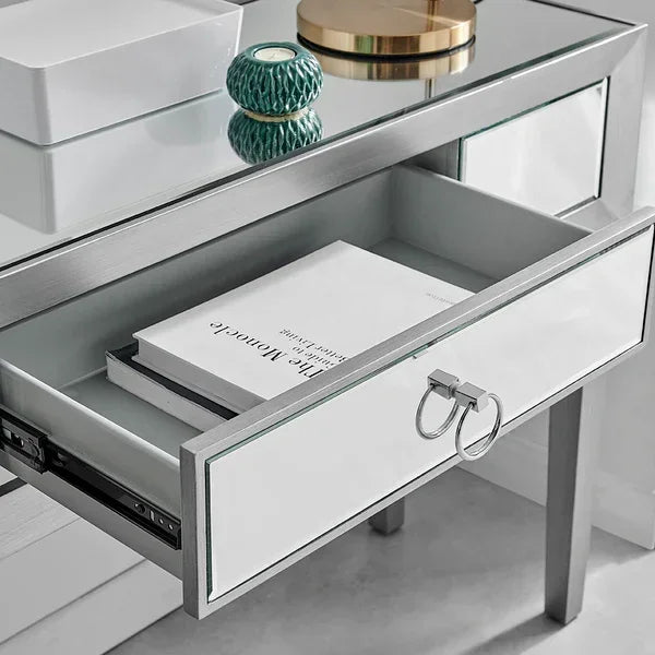 Mirrored dressing table with open drawer, chrome ring handles and decorative tabletop items