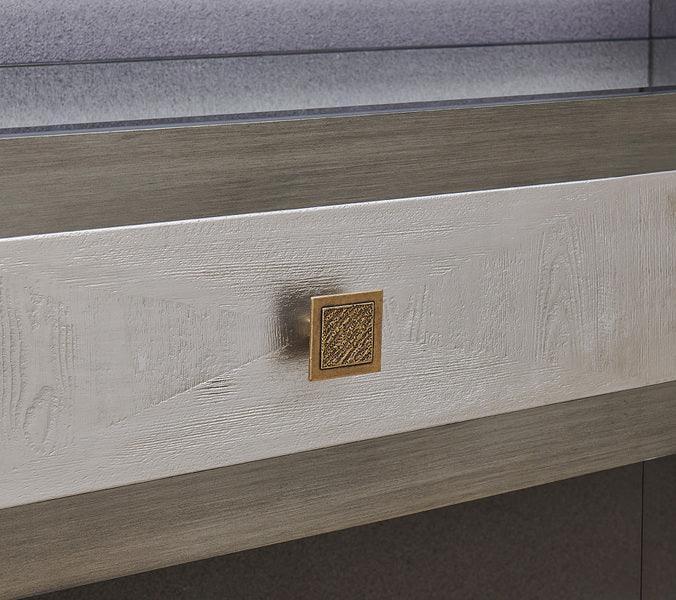 Textured wood furniture drawer with square gold handle, close-up view