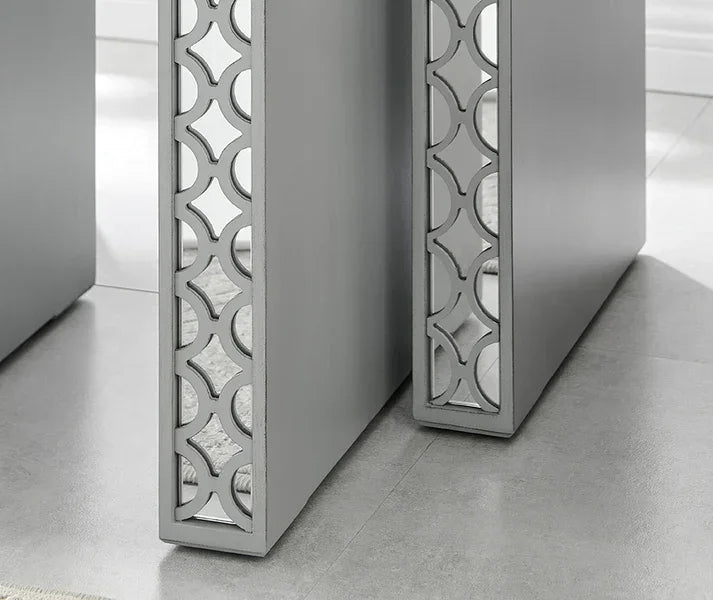 Grey nesting tables with geometric cutout sides and mirrored panels on tiled floor