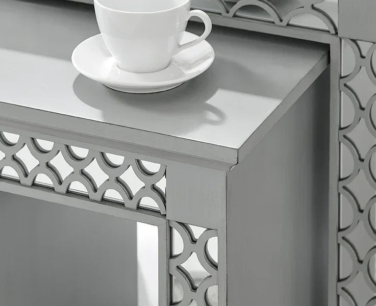 Silver mirrored side table with geometric detailing and white cup placed on top