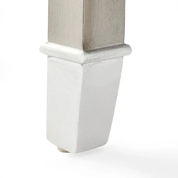 Closeup of wooden furniture leg with metallic finish tapering to a square white base