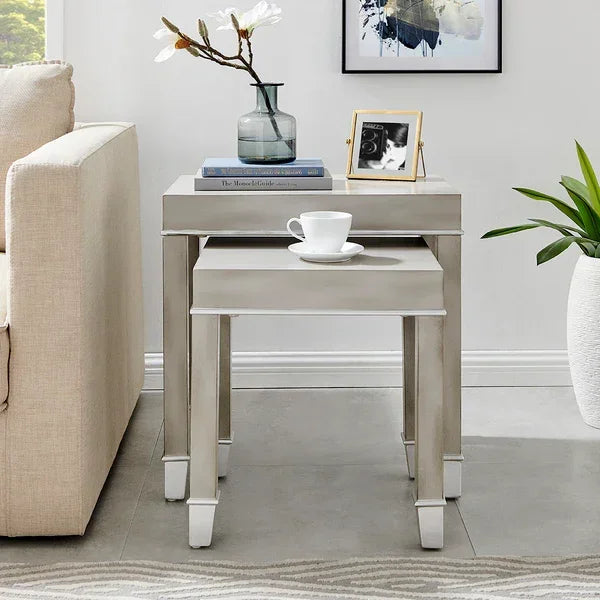 Grey wooden nesting tables beside sofa with vase, books, cup, and photo frame