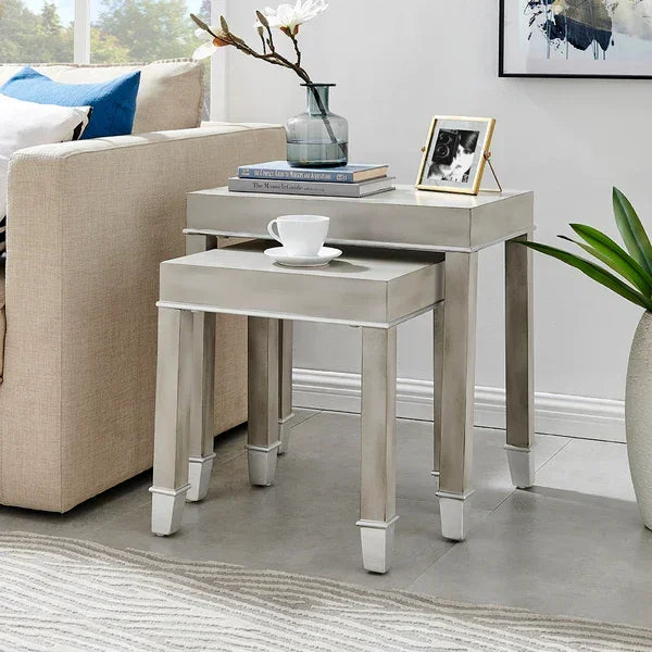 Silver nesting tables set with décor beside beige sofa on tiled living room floor