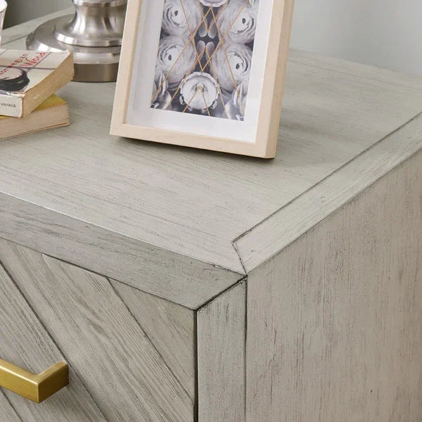 Light wood bedside table with brass handle, books, and a framed photo on top