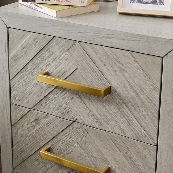 Light wood chest of drawers with herringbone pattern and gold metal handles