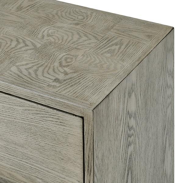Light oak chest of drawers corner with textured wood grain detail and matte finish