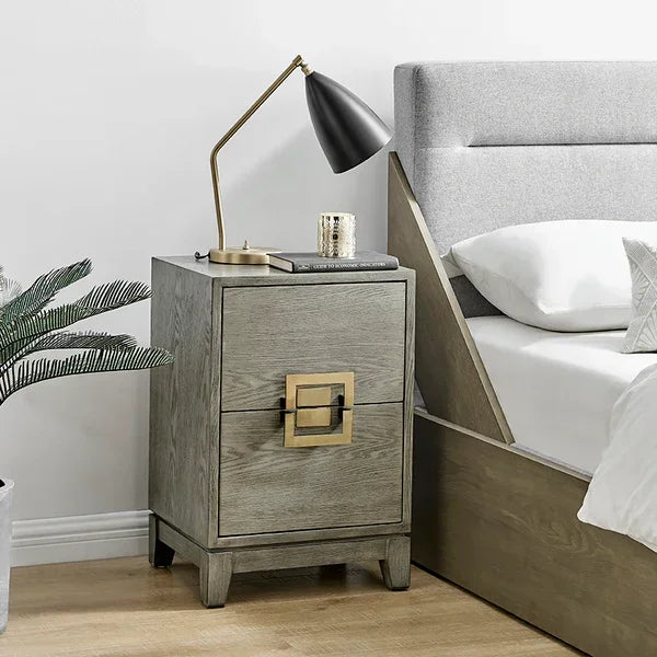Wooden bedside table with gold handle beside upholstered bed and black reading lamp