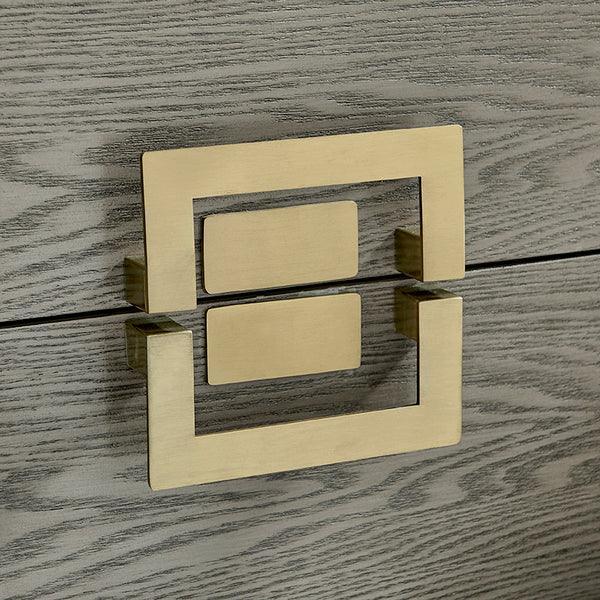 Brushed gold drawer handle on grey oak wood grain chest of drawers