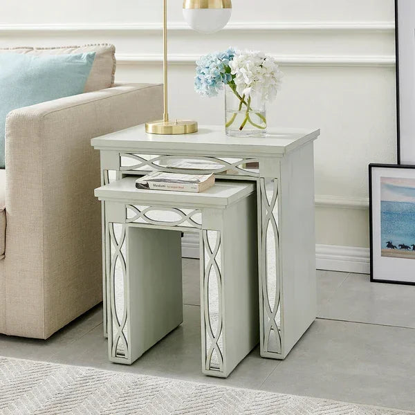 Mirrored nest of tables with decorative trim beside sofa, styled with lamp and flowers