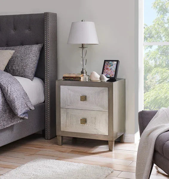 Two drawer bedside table with lamp and decor beside upholstered grey bed