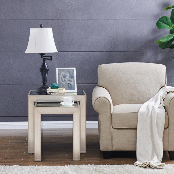 Beige armchair with cream throw next to light wood nesting side tables and table lamp