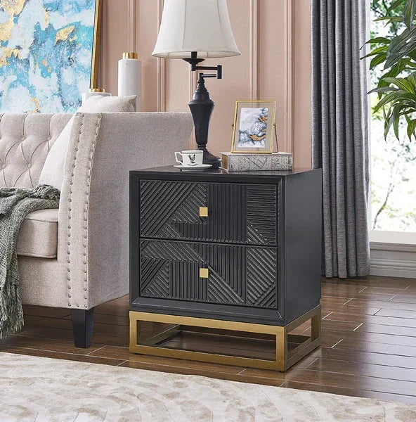 Black geometric bedside table with gold base and two drawers beside cream sofa