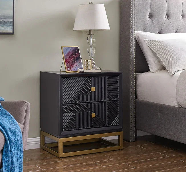 Black geometric bedside table with gold base and two drawers beside upholstered bed