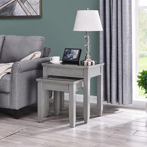Grey wooden nest of tables beside sofa with lamp, photo frame, cup and curtains
