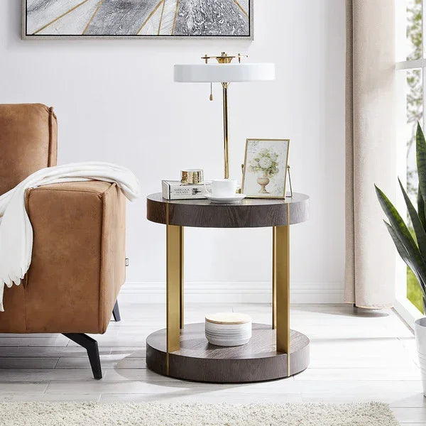 Round wood and gold side table with table lamp beside tan sofa in living room
