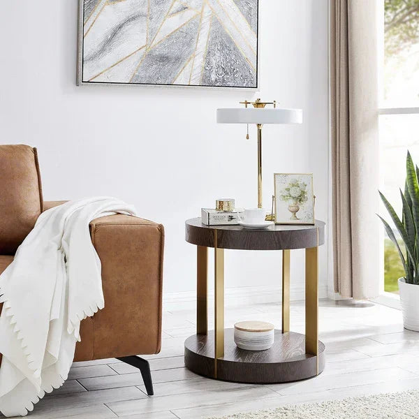 Round side table with gold metal accents beside a tan sofa in a bright living room