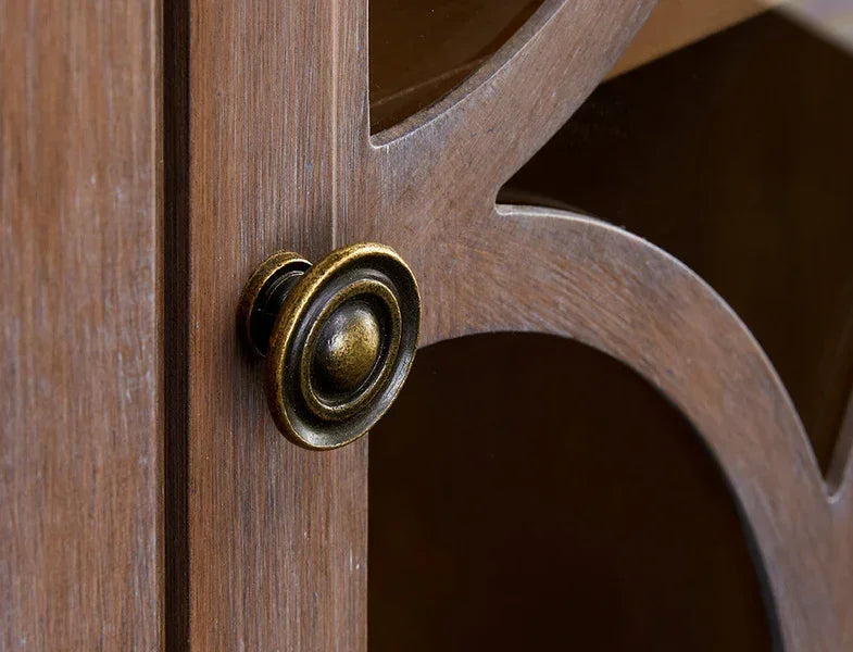 Closeup of cabinet door with brass knob and decorative wood detailing