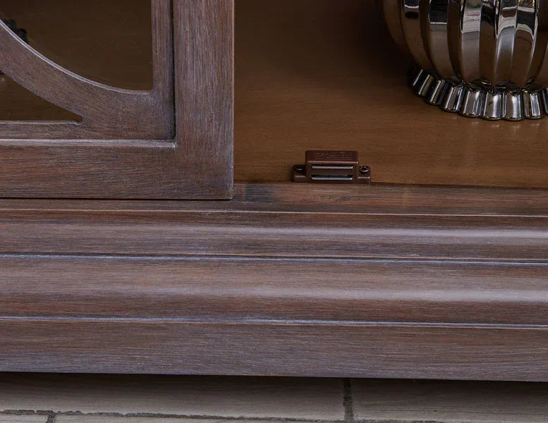 Closeup of wooden sideboard base with panel detail and chrome vase accent