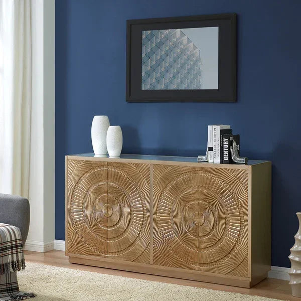 Wooden sideboard with carved circular detail against a navy wall, books and vases on top