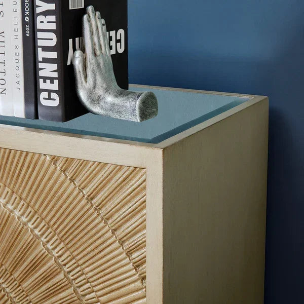Wooden cabinet with textured front panel and glass top, styled with books and silver bookend